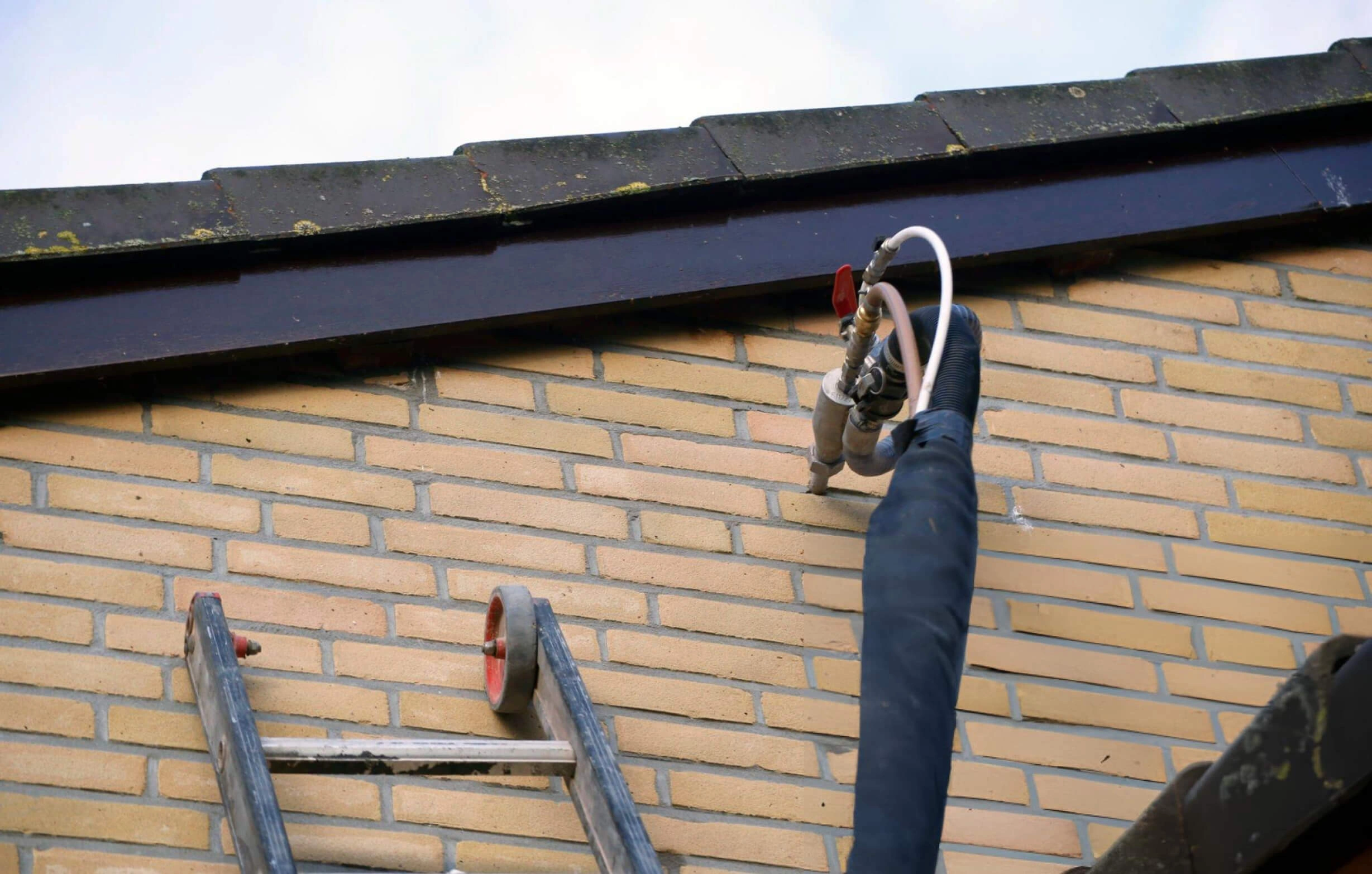 Installer injecting cavity wall insulation into a brick wall