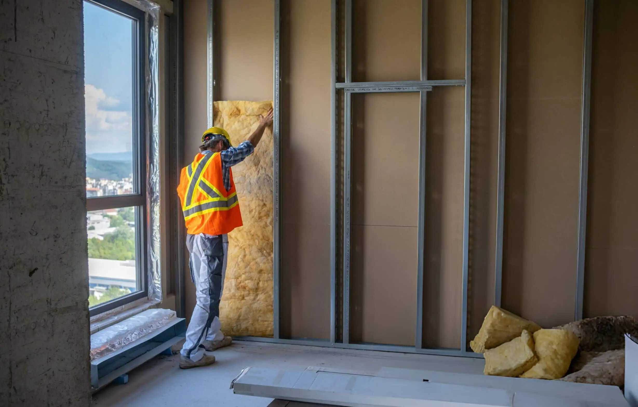 Installer fitting insulation into an internal wall frame